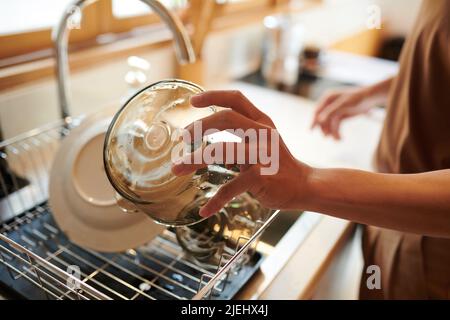 Hände von Mann spülen Glasschüsseln unter Leitungswasser nach dem Frühstück Stockfoto