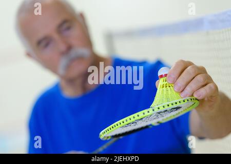 Nahaufnahme eines älteren Mannes, der während eines Badmintonspiels Dienst Stockfoto