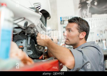 Ein Mechaniker, der am Roller arbeitet Stockfoto