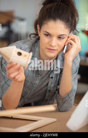 Designer am Telefon untersucht ein Modellhaus aus Holz Stockfoto