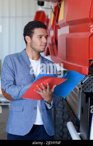 Techniker, der das Dokument nach der Reparatur des Fahrzeugs ausfüllt Stockfoto