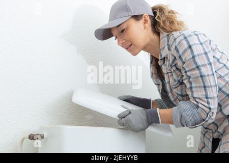 Junge Klempnerin repariert Toilettenspülung Stockfoto