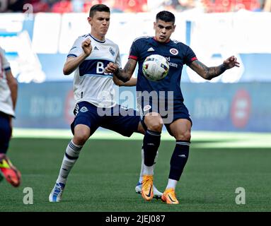 (220627) -- VANCOUVER, 27. Juni 2022 (Xinhua) -- Ranko Veselinovic (L) von Vancouver Whitecaps (Whitecaps) wetteifert mit Gustavo Bou von der New England Revolution während des Spiels der Major League Soccer (MLS) 2022 am BC Place in Vancouver, Kanada, am 26. Juni 2022. (Foto von Andrew Soong/Xinhua) Stockfoto