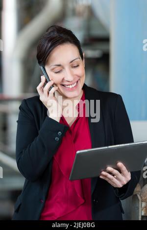 Fabrikleiterin auf ihrem tragbaren Telefon Stockfoto