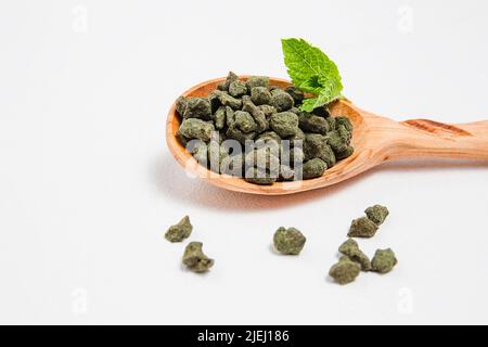 Frischer Oolong-Tee mit Ginseng. Ein Stapel gerollter Tees in einem Holzlöffel. Teesortiment im Geschäft. Chinesischer oder orientalischer gesunder, koffeinhaler Tee. Weiß, Bac Stockfoto