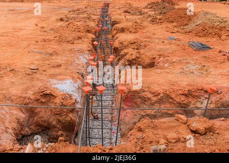 Eine Baustelle wird mit Stahl für ihre Gründung durch einen Graben vorbereitet Stockfoto