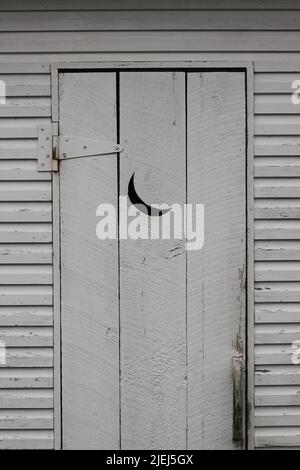 Nebengebäude mit einem Mond, der in die Holztür gehauen wurde. Stockfoto