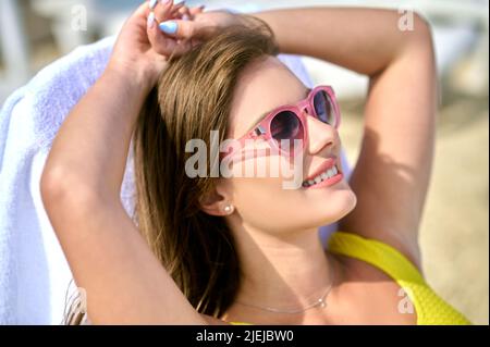 Fröhliche hübsche Dame, die in der Sonne liegt Stockfoto