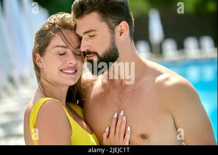 Romantische Dame umarmt einen jungen dunkelhaarigen Mann Stockfoto
