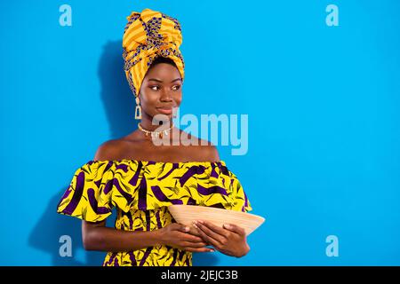 Foto von jungen schönen lächelnden afrikanischen Frau in Turban Look Copyspace halten Tonplatte isoliert auf blauem Hintergrund Stockfoto