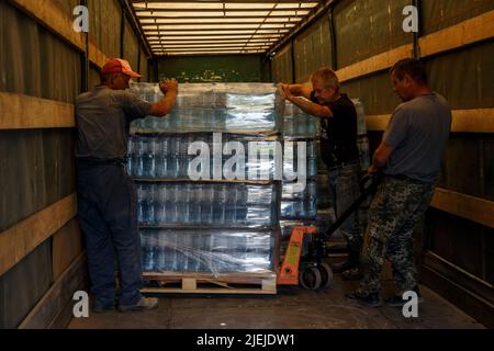 REGION ZAKARPATTIA, UKRAINE - 24. JUNI 2022 - Arbeiter laden eine Palette von abgefülltem Wasser, das vom Memory and Roots Zakarpattya Fund bereitgestellt wird, von einem Lastwagen Stockfoto