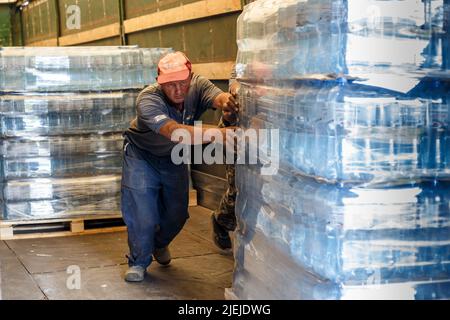 REGION ZAKARPATTIA, UKRAINE - 24. JUNI 2022 - Arbeiter laden eine Palette von abgefülltem Wasser, das vom Memory and Roots Zakarpattya Fund bereitgestellt wird, von einem Lastwagen Stockfoto