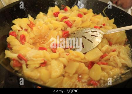Großer Löffel in einem Topf mit Kartoffeln und Paprika mit Zwiebeln für eine Tortilla Tapas Stockfoto