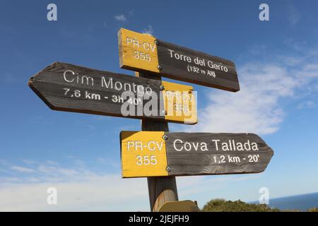 Buntes Schild auf Holz am Sandstrand mit Busch um Stockfoto