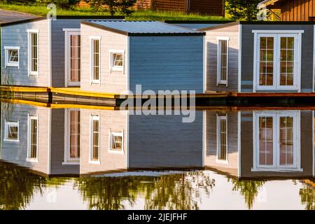 Schwimmende Hütten mit schöner Reflexion auf dem Seewasser an einem sonnigen Tag. Das Leben auf einem schwimmenden Haus ist sehr attraktiv. Stockfoto