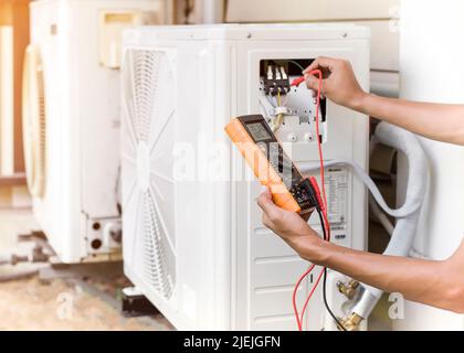 Luftreparaturmechaniker mit Messgeräten zum Befüllen von industriellen Klimaanlagen und zur Überprüfung der Wartung der Außenluftkompressoreinheit. Stockfoto