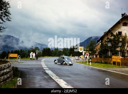 Volkswagen VW-Käfer-Wagen von der Hauptstraße in Richtung Hinterzarten, Baden-Württemberg, Deutschland Juli 1959 Bromley-Roller-Club-Mitglieder an der Ecke diskutieren Stockfoto