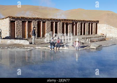 Touristen sind im heißen Wasser-Naturpool der Geysire El Tatio in Chile. El Tatio ist ein Geysir-Feld im Norden Chiles. Es ist das größte Stockfoto