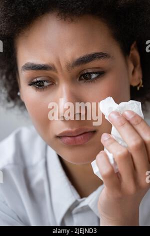 Nahaufnahme einer afroamerikanischen Frau im weißen Hemd, die weint und Serviette hält Stockfoto