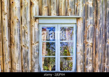 Fenster auf einem alten Häuschen mit unbemalten Holzwänden Stockfoto