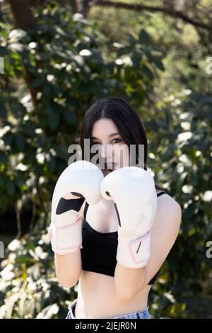 Junge Boxerin mit weißen Handschuhen in einem Park Stockfoto