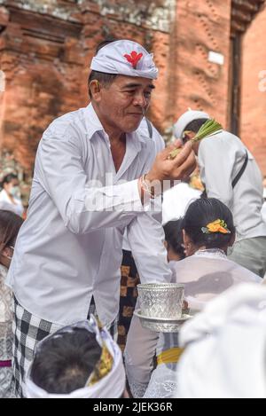 Denpasar, Indonesien. 26.. Juni 2022. Ein hinduistischer religiöser Führer spritzt während der Zeremonie Weihwasser auf die Anhänger. Balinesische Hindus versammeln sich im Großen Tempel von Petiran in Kesiman, um die Ngerebong-Zeremonie durchzuführen, was bedeutet, die Energie der Welt auszugleichen und auch die Harmonie zwischen Menschen und Göttern, Menschen miteinander und Menschen mit ihrer Umgebung zu bewahren. Ngerebong bedeutet „Versammlung“ in Bali, das seit 1937 zweimal im Jahr stattfindet. Kredit: SOPA Images Limited/Alamy Live Nachrichten Stockfoto