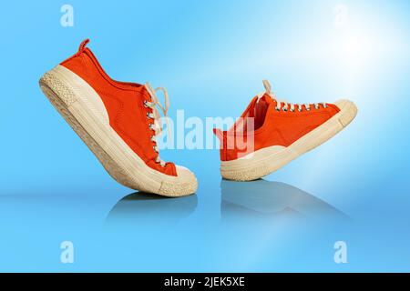 Auf blauem Hintergrund laufen weiße, orangefarbene Schuhe. Turnschuhe oder Sportschuhe isoliert. Sportschuhe. Fitness, Sport, Trainingskonzept. Stadt Stockfoto