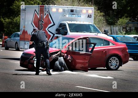 Autounfall rotes Auto auf der Straße mit Krankenwagen im Hintergrund zertrümmert vorderen Stoßfänger Stockfoto