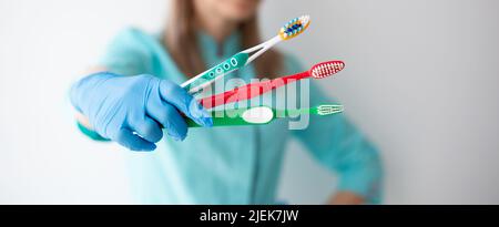 Drei verschiedene Zahnbürsten in der Hand von Hygienist, Zahnarzt. Stockfoto