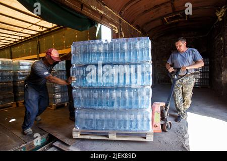 Region Zakarpattia, Ukraine - 24. Juni 2022 - Männer haben eine Palette von abgefülltem Wasser aus dem Memory and Roots Zakarpattya Fund in einen Güterwagen gesteckt, der die humanitäre Fracht in die vom Krieg verwüsteten Städte in der Ostukraine, Region Zakarpattia, Westukraine, bringen wird. Dieses Foto kann nicht in der Russischen Föderation verteilt werden. Foto von Serhii Hudak/Ukrinform/ABACAPRESS.COM Stockfoto