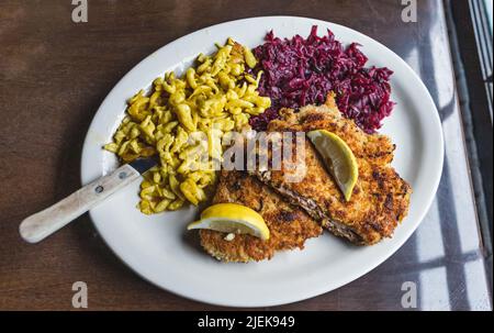 Deutsches Schweinsschnitzel mit einer Seite aus süß-saurem Purpurkohl und Käsespätzle Stockfoto