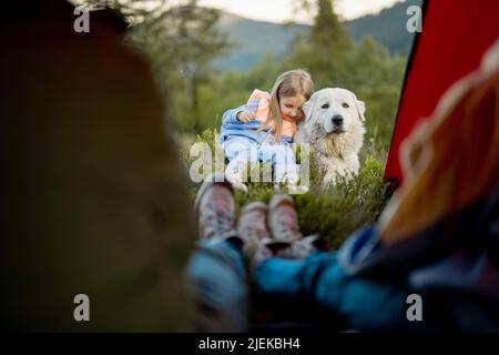 Niedliches kleines Mädchen umarmt sich mit einem Hund während der Reise in die Natur Stockfoto