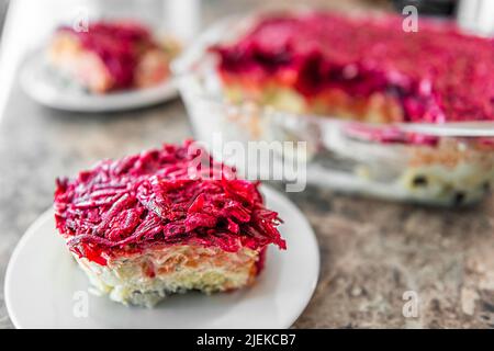 Traditionelle russische Salatgericht Seledka pod Shuba Hering unter Pelzmantel Nahaufnahme der Platte serviert mit Rüben mit Kartoffeln, Hering, Carro geschichtet Stockfoto