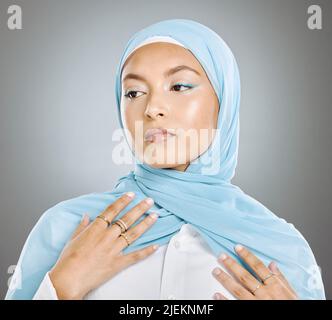 Eine strahlende, schöne muslimische Frau, isoliert vor grauem Copyspace-Hintergrund. Junge Frau mit einem Hijab oder einem Kopftuch, das ihre Wimpern verlängert Stockfoto