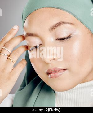 Nahaufnahme einer glühenden, schönen muslimischen Frau, isoliert vor grauem Studiohintergrund. Junge Frau mit einem Hijab oder einem Kopftuch, das ihre Wimpern zeigt Stockfoto