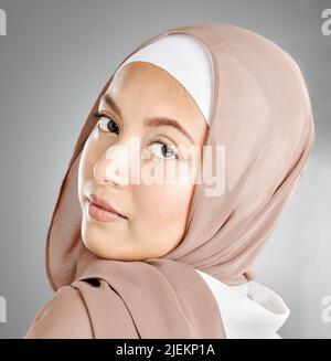 Porträt eines Hijab, der im Studio eine traditionelle muslimische Frau im arabischen Stil trägt. Kopfschuss des stolzen kulturellen arabers mit schöner Haut gegen Grau Stockfoto