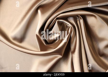 Hintergrund aus beigefarbenem Satin-Stoff. Textur aus Viskose ist brauner Hintergrund Stockfoto