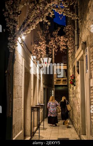 Menschen, die nachts in einer engen Gasse im Diokletianspalast, Split, Kroatien, spazieren gehen Stockfoto