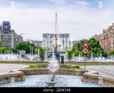 Bukarest, Rumänien - 2022. April: Die Wasserfontänen vom Unirii-Platz (Piata Unirii) mit dem Palast des Parlaments, auch bekannt als Volkshaus in t Stockfoto