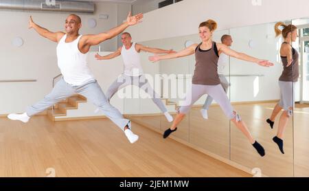 Positive junge Erwachsene springen während des Tanztrainings Stockfoto