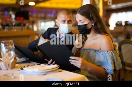 Pärchen haben sich beim Lesen der Speisekarte im Restaurant für die Mahlzeiten entschieden Stockfoto