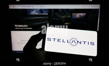 Person, die das Smartphone mit dem Logo des Automobilherstellers Stellantis N.V. auf dem Bildschirm vor der Website hält. Konzentrieren Sie sich auf die Telefonanzeige. Stockfoto