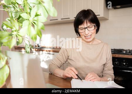 Schöne stilvolle ältere Frau, die zu Hause arbeitet. Stockfoto