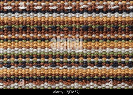 Makro-Struktur in Leinwandbindung. Stoffhintergrund mit horizontalen Streifen aus weißen, gelben, grünen, braunen und schwarzen Farben. Farbenfrohe textile Oberfläche. Stockfoto