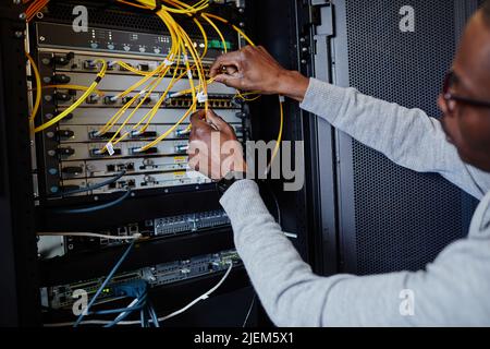 Nahaufnahme des IT-Technikers, der während der Einrichtung des Datennetzwerks Kabel im Serverraum anschließt, Speicherplatz kopieren Stockfoto