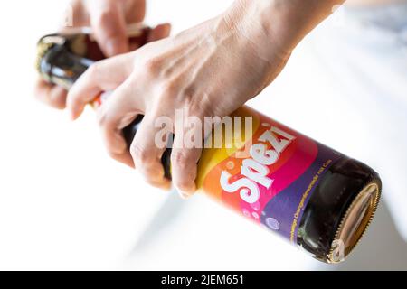 München, Deutschland. 27.. Juni 2022. Eine junge Frau öffnet eine Flasche Spezi für eine Illustration. Kredit: Lennart Preiss/dpa/Alamy Live Nachrichten Stockfoto