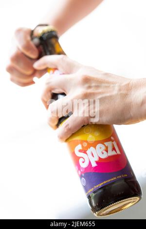 München, Deutschland. 27.. Juni 2022. Eine junge Frau öffnet eine Flasche Spezi für eine Illustration. Kredit: Lennart Preiss/dpa/Alamy Live Nachrichten Stockfoto