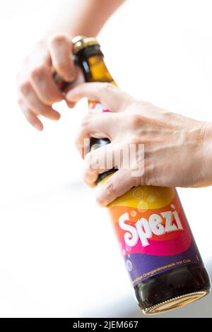 München, Deutschland. 27.. Juni 2022. Eine junge Frau öffnet eine Flasche Spezi für eine Illustration. Kredit: Lennart Preiss/dpa/Alamy Live Nachrichten Stockfoto