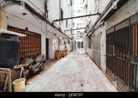 San Juan, Sevilla, Spanien - 11 2022. Juni: Eine schmale Gasse mit hohen Mauern in einem armen, marginalisierten Teil der Innenstadt Stockfoto