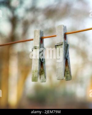Zwei hölzerne Wäscheklammern an einer Linie.zwei alte hölzerne Wäscheklammern, die an einer Wäscheleine in einem sonnigen Garten hängen. Altmodische Werkzeuge zum frischen Aufhängen Stockfoto